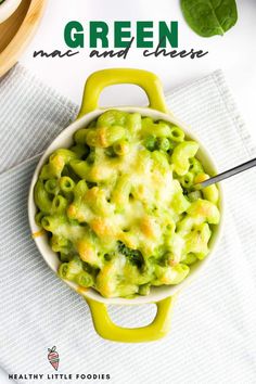 green macaroni and cheese is in a bowl with a spoon on the side