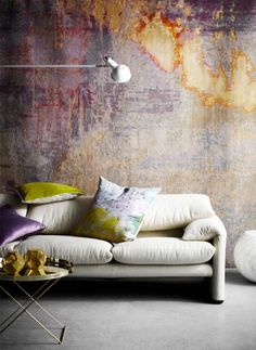 a white couch sitting in front of a wall covered in colorful pillows and throw pillows