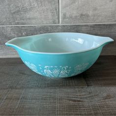 a blue and white bowl sitting on top of a wooden table next to a tile wall