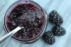 blackberry jam in a glass jar with spoon and blackberries on the side, ready to be eaten