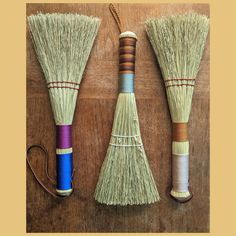 three different types of brooms sitting on top of a wooden table