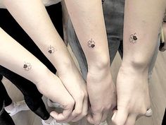 three people with matching tattoos holding hands