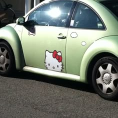 a green car with a hello kitty sticker on it's side