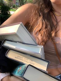 a woman is holding several books in her hands