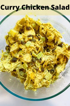 a glass bowl filled with chicken salad on top of a white table next to a yellow wall