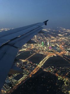 an airplane wing flying over a city at night