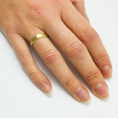 a woman's hand with a gold ring on her left hand, against a white background