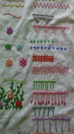 several different types of beaded hair clips on a white cloth with flowers and leaves