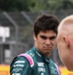 a man in a green racing suit is talking to another man with his head shaved