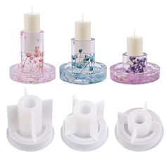 four candle holders with candles in them sitting next to each other on top of plates