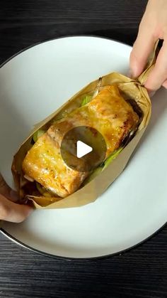 two hands grabbing food out of a paper bag on a white plate with a black table