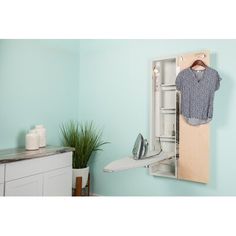 an ironing board mounted to the side of a wall with clothes hanging on it