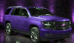 a purple suv is parked in front of a brick wall with lights on the side