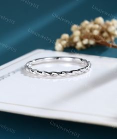 a ring sitting on top of a white plate next to a flower and dried plant