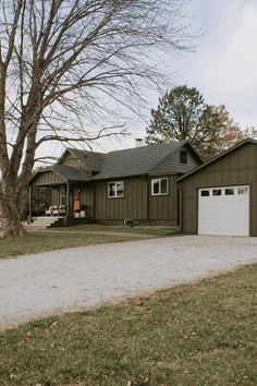 a brown house with two garages and trees in the background