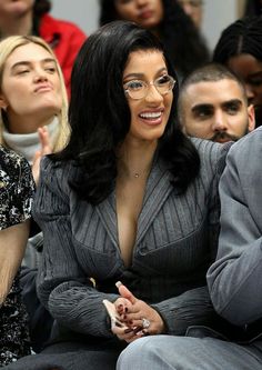 a woman wearing glasses sitting in front of other people