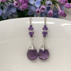 The Wisteria Path earrings weave a delicate story of rich blooms and delicate petals. These earrings feature beautiful, tender purple amethyst that have been intricately hand-carved with a unique starburst pattern and wrapped with fine sterling silver. Gracefully suspended from marquise French ear wires that are embellished with blossoms of petite, micro-faceted amethyst. Swirled, vine-like detailing on the ear wires give an extra feminine touch to these lovelies. Very lightweight, unique and oh Elegant Lavender Earrings With Ear Wire, Purple Natural Stone Drop Earrings, Lavender Amethyst Teardrop Earrings, Purple Amethyst Teardrop Crystal Earrings, Lavender Briolette Gemstone Earrings, Handmade Lavender Crystal Drop Earrings, Lavender Earrings With Natural Stones For Gift, Handmade Amethyst Crystal Earrings, Lavender Amethyst Gemstone Earrings