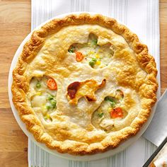 a chicken pot pie on a white plate with a knife and fork next to it