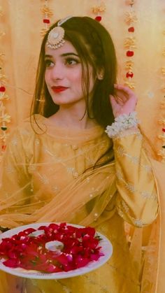 a woman in a yellow dress holding a plate with roses on it