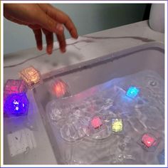 a person is reaching for some dices in the sink with water on top of it