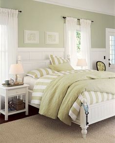 a bedroom with green and white bedding, two nightstands on either side of the bed