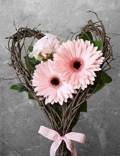 pink flowers in a heart shaped vase with ribbon tied around the top and two white daisies