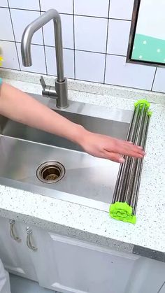 a person cleaning a kitchen sink with green sponges