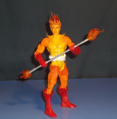 the action figure is holding two swords in one hand and an orange flame on the other