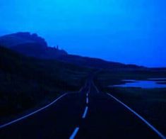 an empty road in the middle of nowhere with blue sky and water on either side