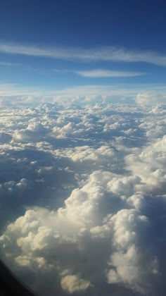 the view from an airplane window looking down on clouds and blue sky with white puffy clouds