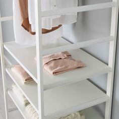 a white shelf with towels and clothes on it