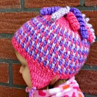 a small child wearing a pink and purple knitted hat