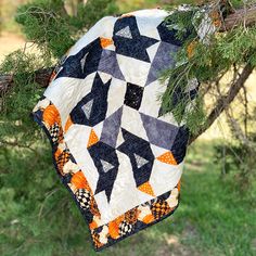 a patchwork quilt hanging from a tree branch