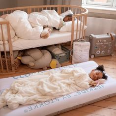 a small child laying in a bed next to a crib with stuffed animals on it