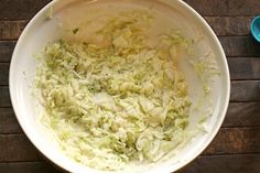 a bowl filled with shredded cabbage on top of a wooden table