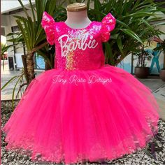 a pink dress with gold sequins on the chest and name barbie written on it