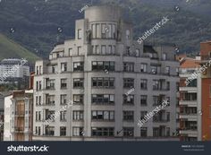 an apartment building with many windows and balconies in front of a mountain range