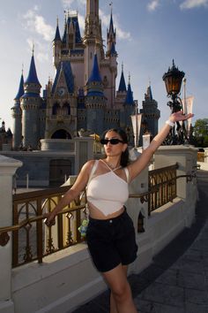 a woman standing in front of a castle with her arms up and hands out to the side