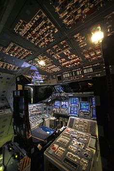 an airplane cockpit with many electronic devices and lights on the ceiling, all lit up at night