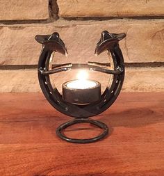 a metal candle holder with two dolphins on it's sides and a lit candle in the middle