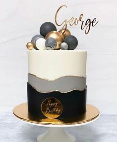 a birthday cake decorated with black, white and gold decorations