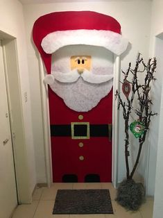 a door decorated to look like santa clause with a tree in front of it and an entrance mat on the floor