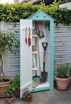 an outdoor garden shed with gardening tools in the door and potted plants on the side