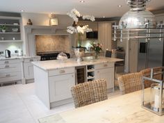 a large kitchen with an island and wicker chairs around the table, along with stainless steel appliances