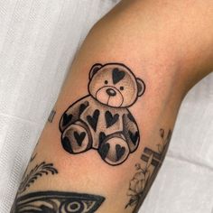 a black and white teddy bear tattoo on the arm