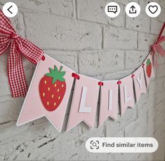 a pink banner with a strawberry hanging from it's side on a brick wall