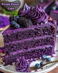 a slice of purple velvet cake on a white plate with blueberries and blackberries