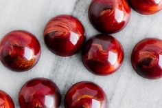 six red marbles are arranged on a white surface