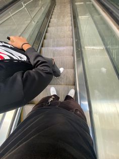 two people are riding down an escalator with their feet on the glass railing