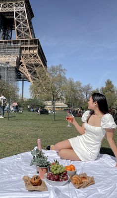 a woman sitting in front of the eiffel tower holding a glass of wine